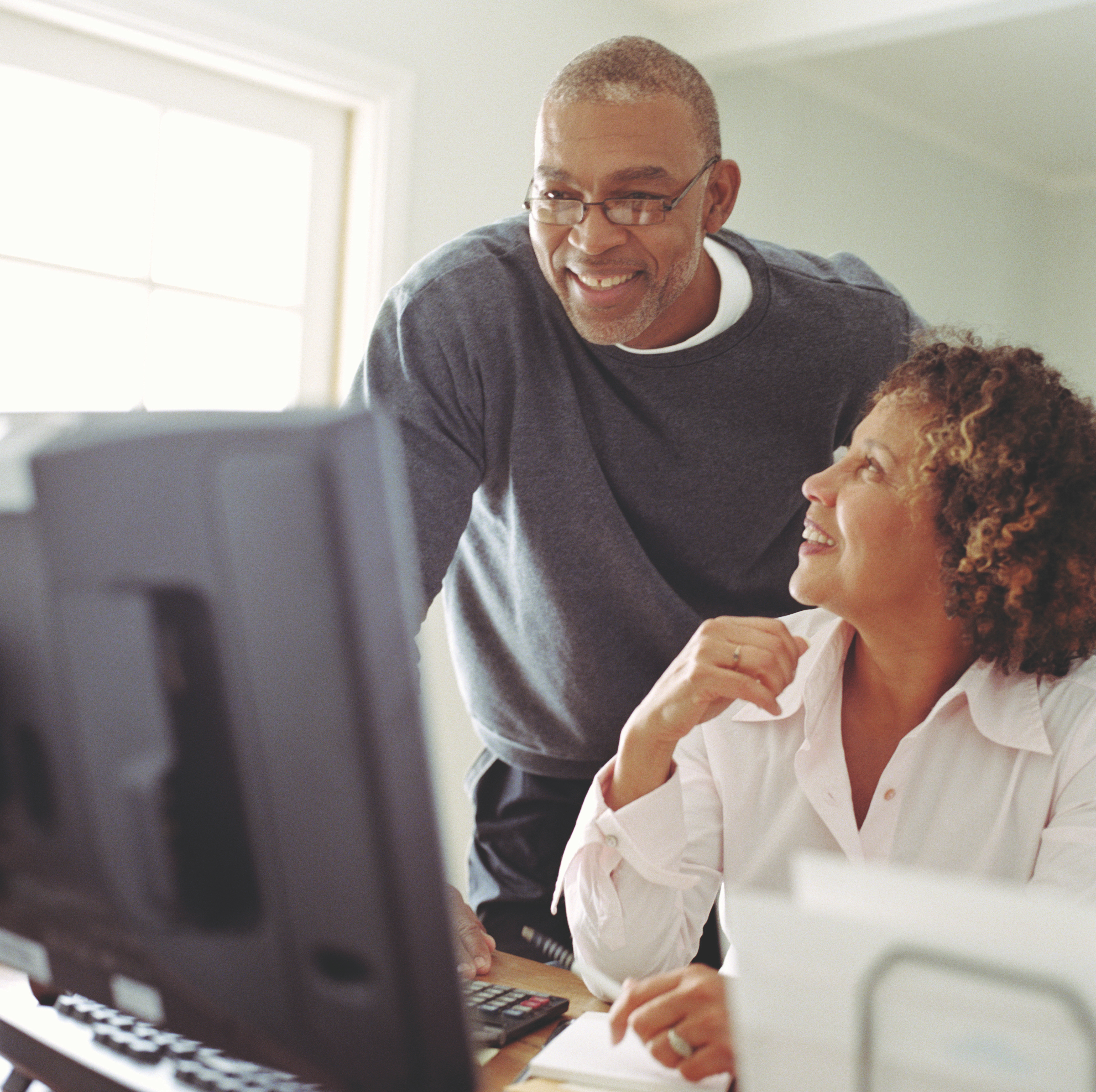 Husband Looking Over Wife Working on a Computer